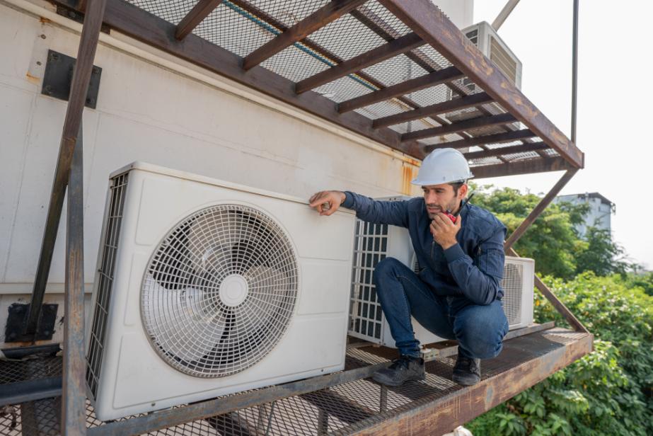HVAC technician inspecting air conditioning system on rooftop