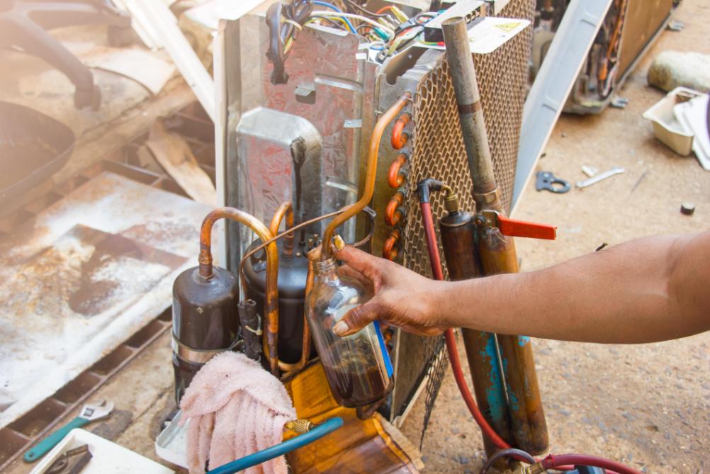 HVAC technician working on furnace and refrigerant system components