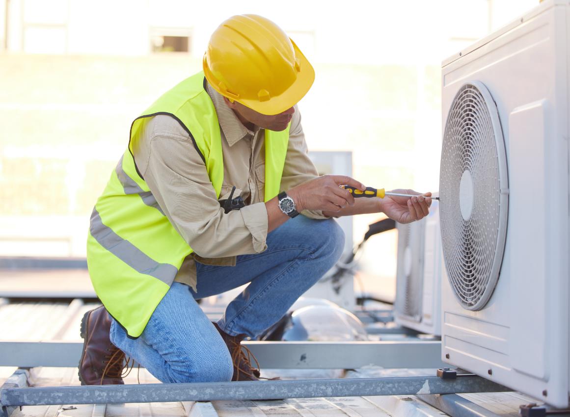 Professional HVAC technician performing air conditioning repair on rooftop