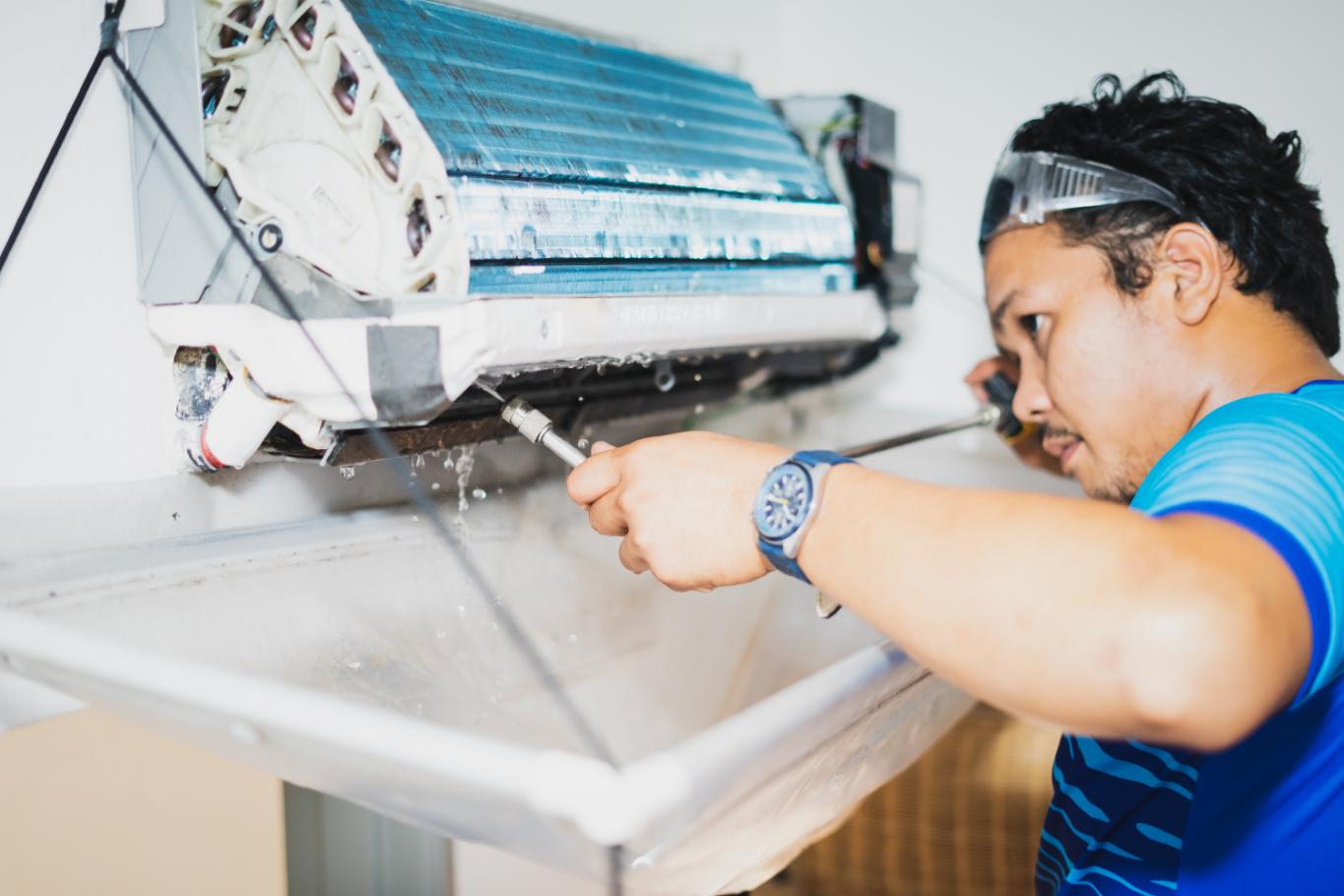 Professional technician cleaning and servicing indoor air conditioning unit